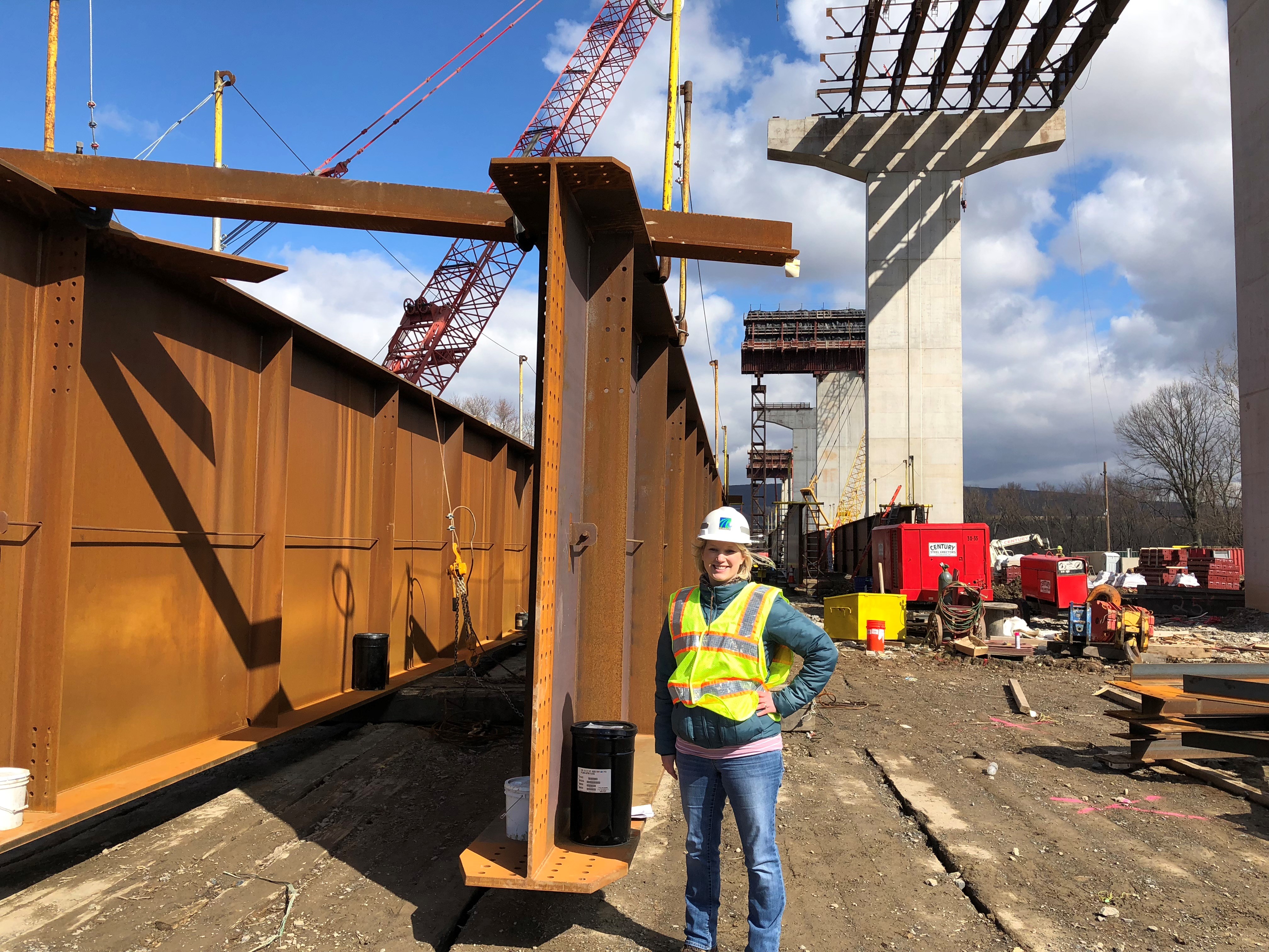 Maggie Jackson standing with construction gear on in front of a large steel bridge beam.