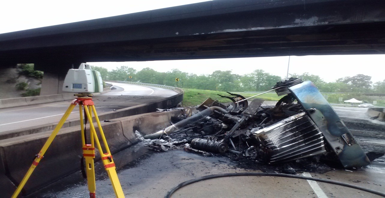 static lidar tripod in front of burned tractor-trailer below the bridge