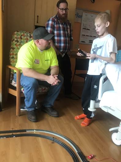 Parker, 9, shows his trains in his hospital room to Brian Wingrove, sitting, and Adam Zweig.