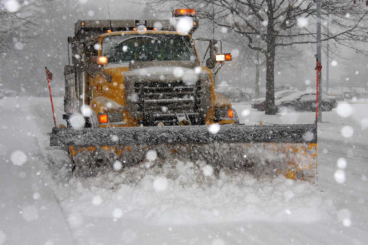 Yellow PennDOT plow driving in heavy snow.