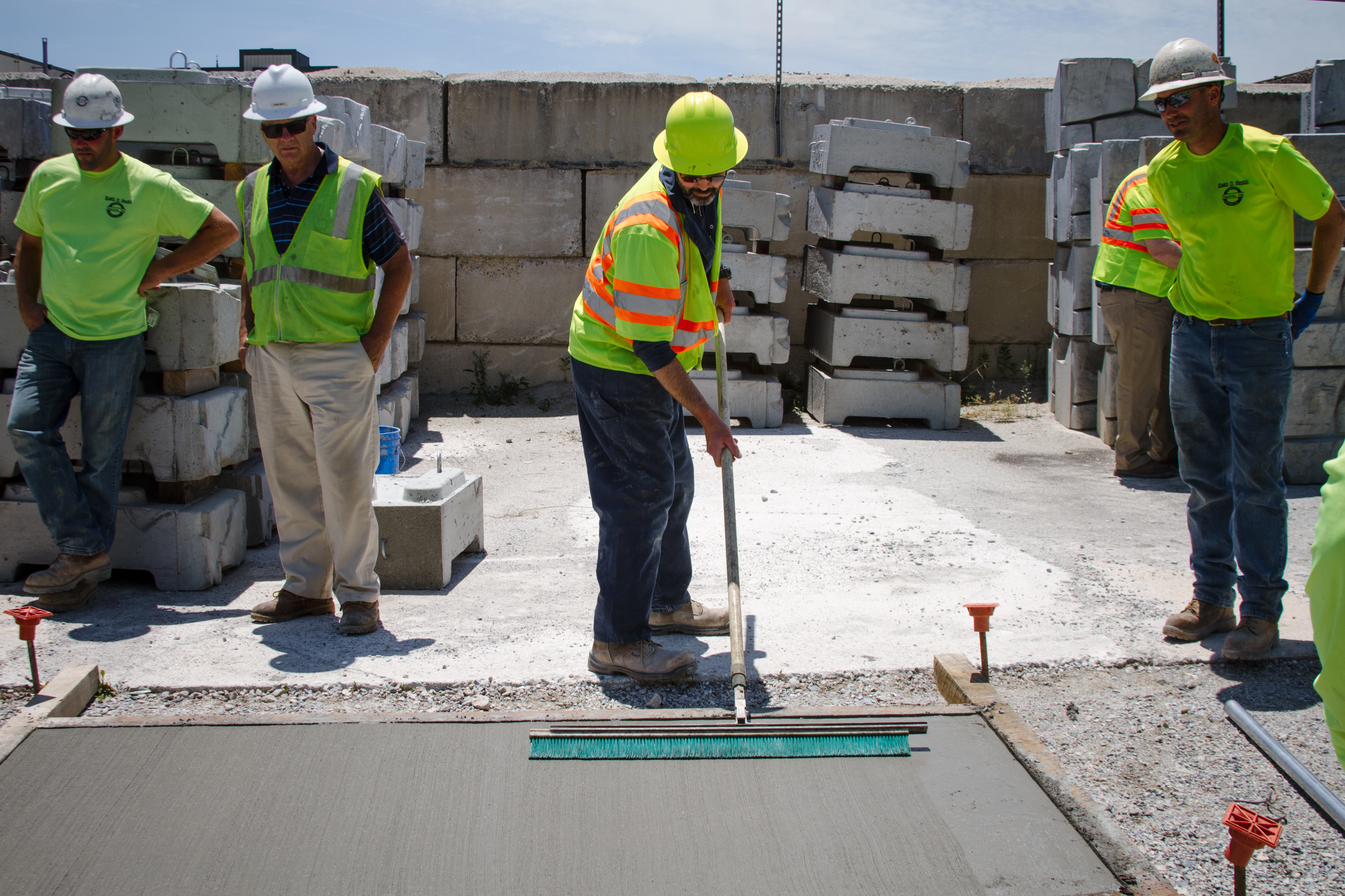 An image of Certified Concrete Finishers Course attendees standing in front of a simulated concrete pad practicing their finishing skills as part of the hands-on portion of the training.