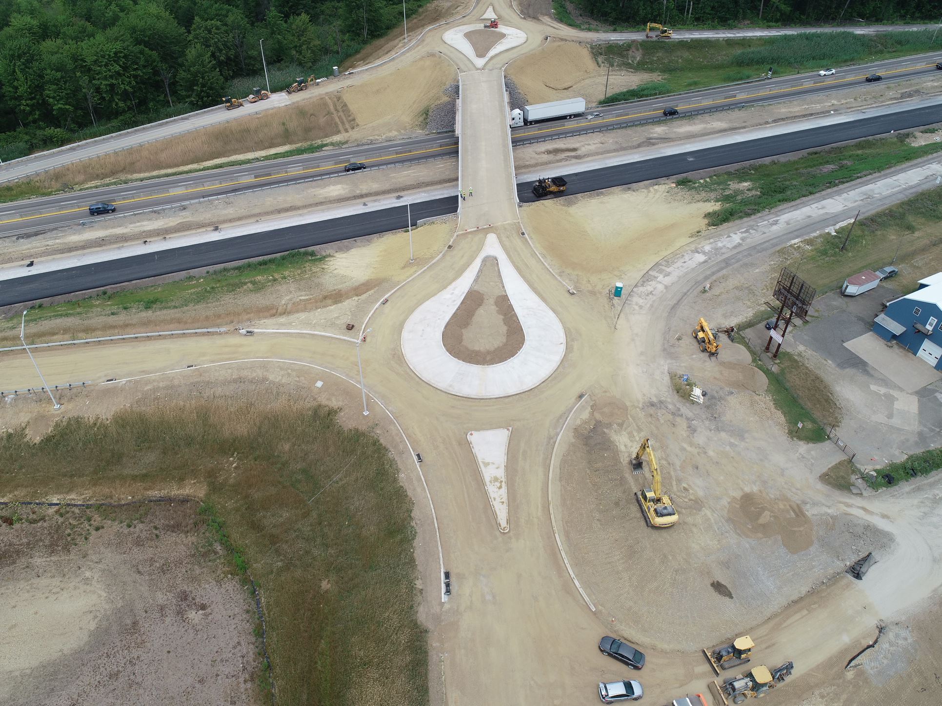 Overhead view of two teardrop roundabouts being constructed over a major highway.