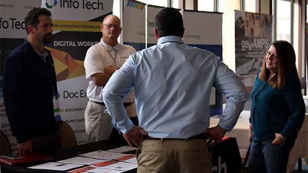 couple of regional innovation day attendees talking to a person at the booth table