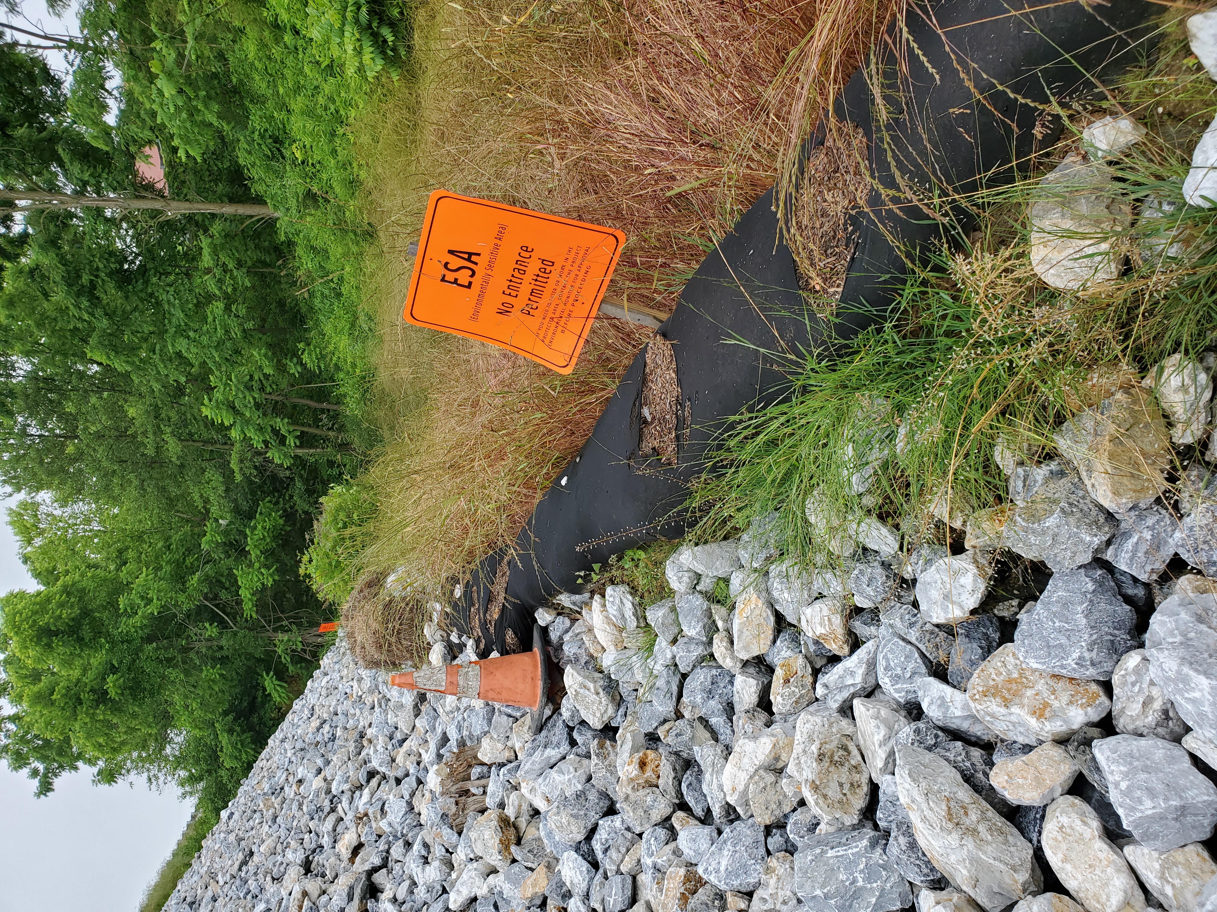Orange Environmentally Sensitive Area Sign along slope in construction zone.