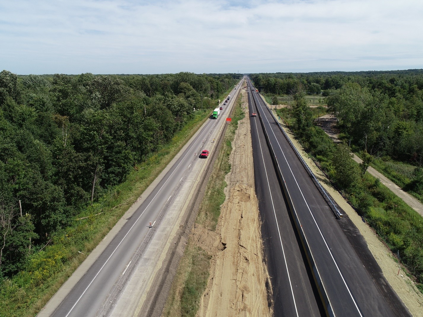 Overhead shot of a four-lane interstate with a grass media and trees on either side.