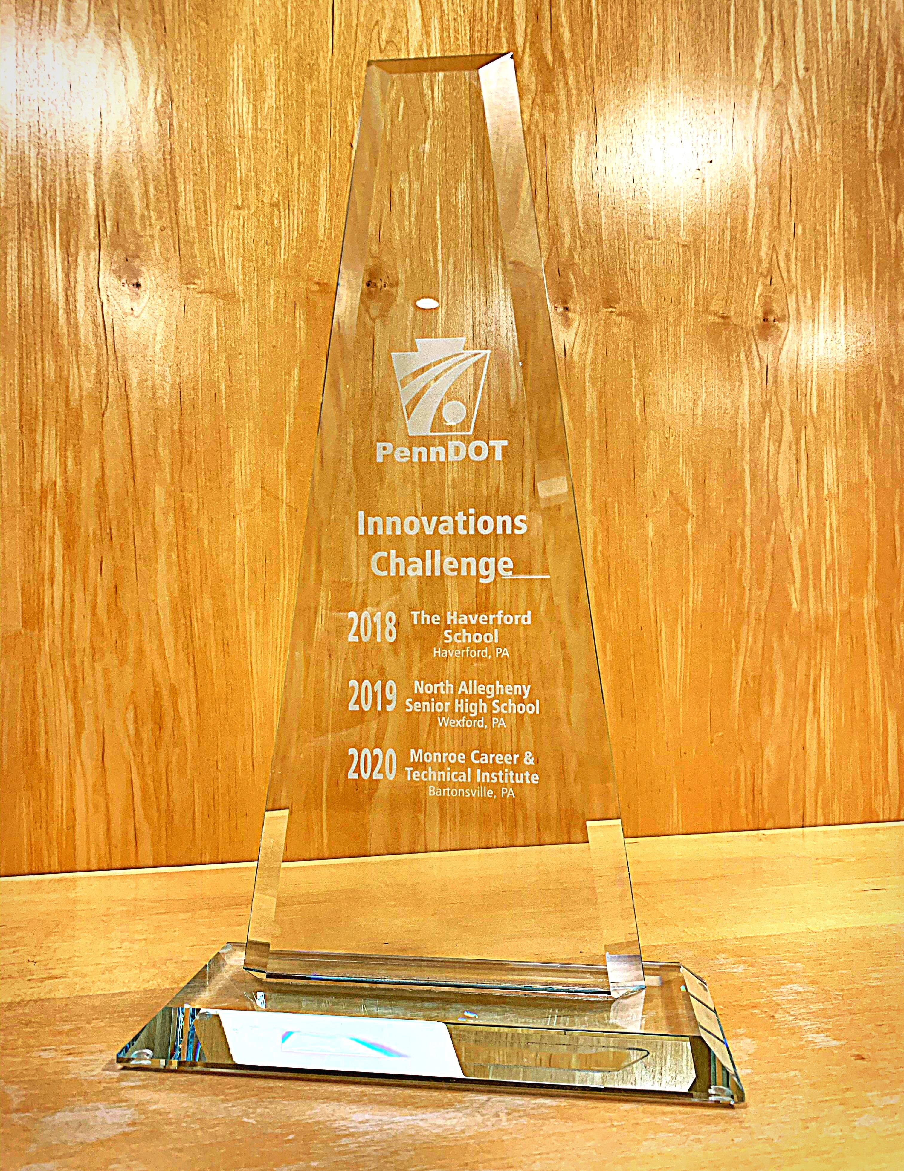 A glass award shaped like a safety cone with the engraving of three years of Innovation Challenge winners on it.