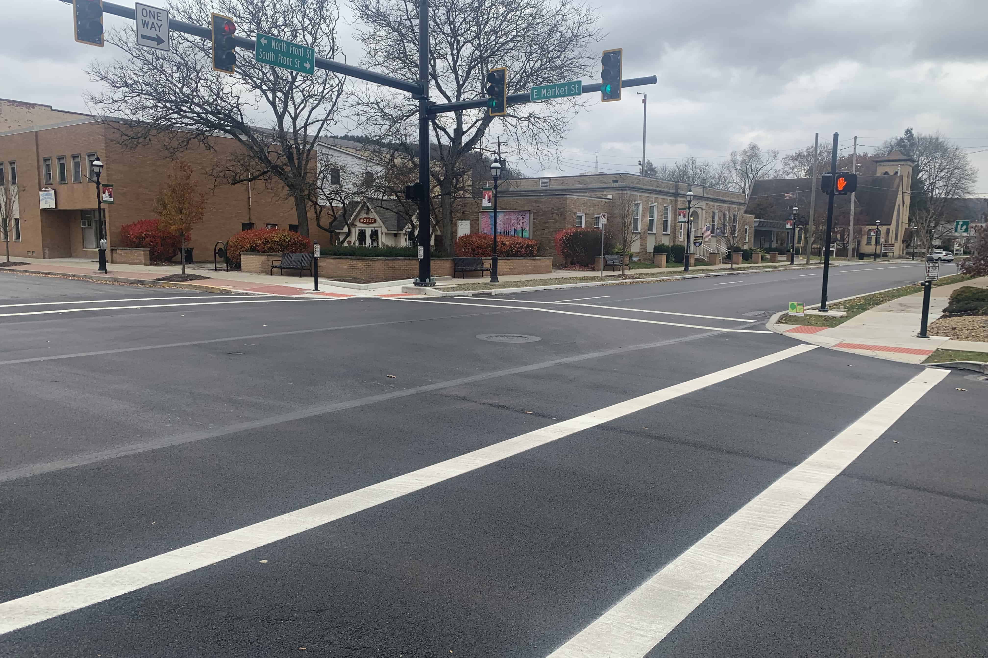 A freshly paved and lined four-way intersection with traffic lights.