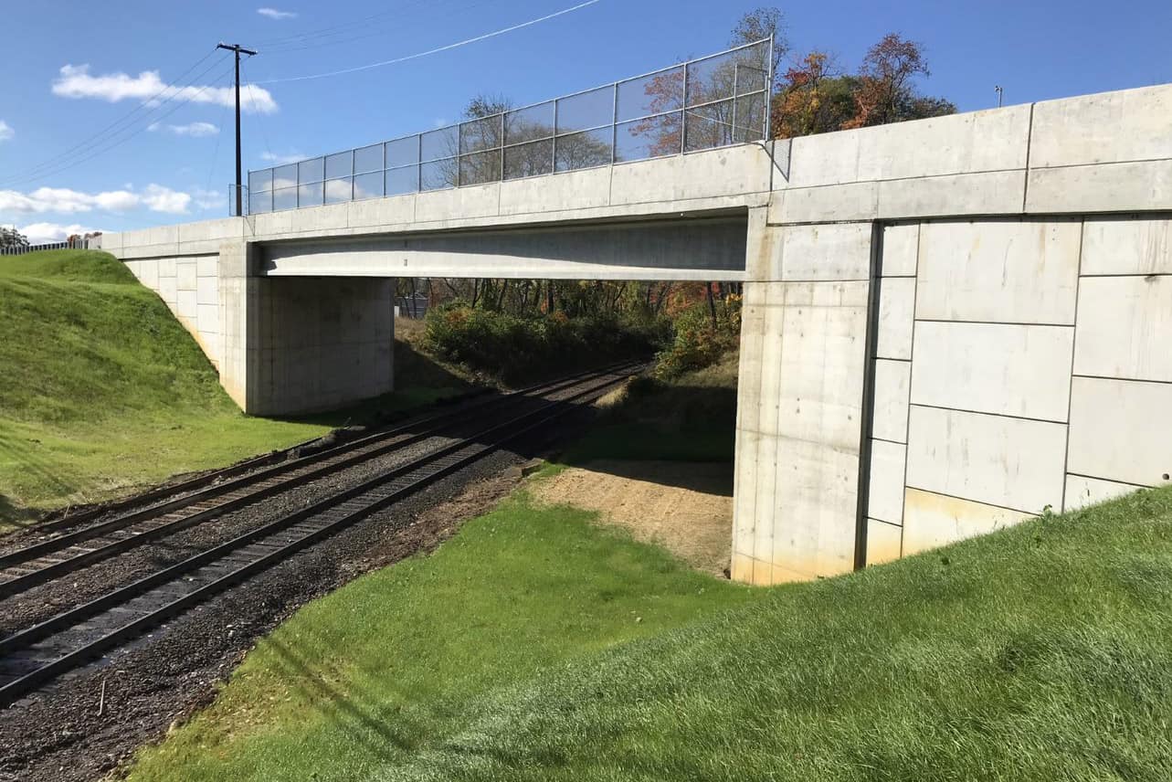 A concrete bridge stands over railroad tracks.