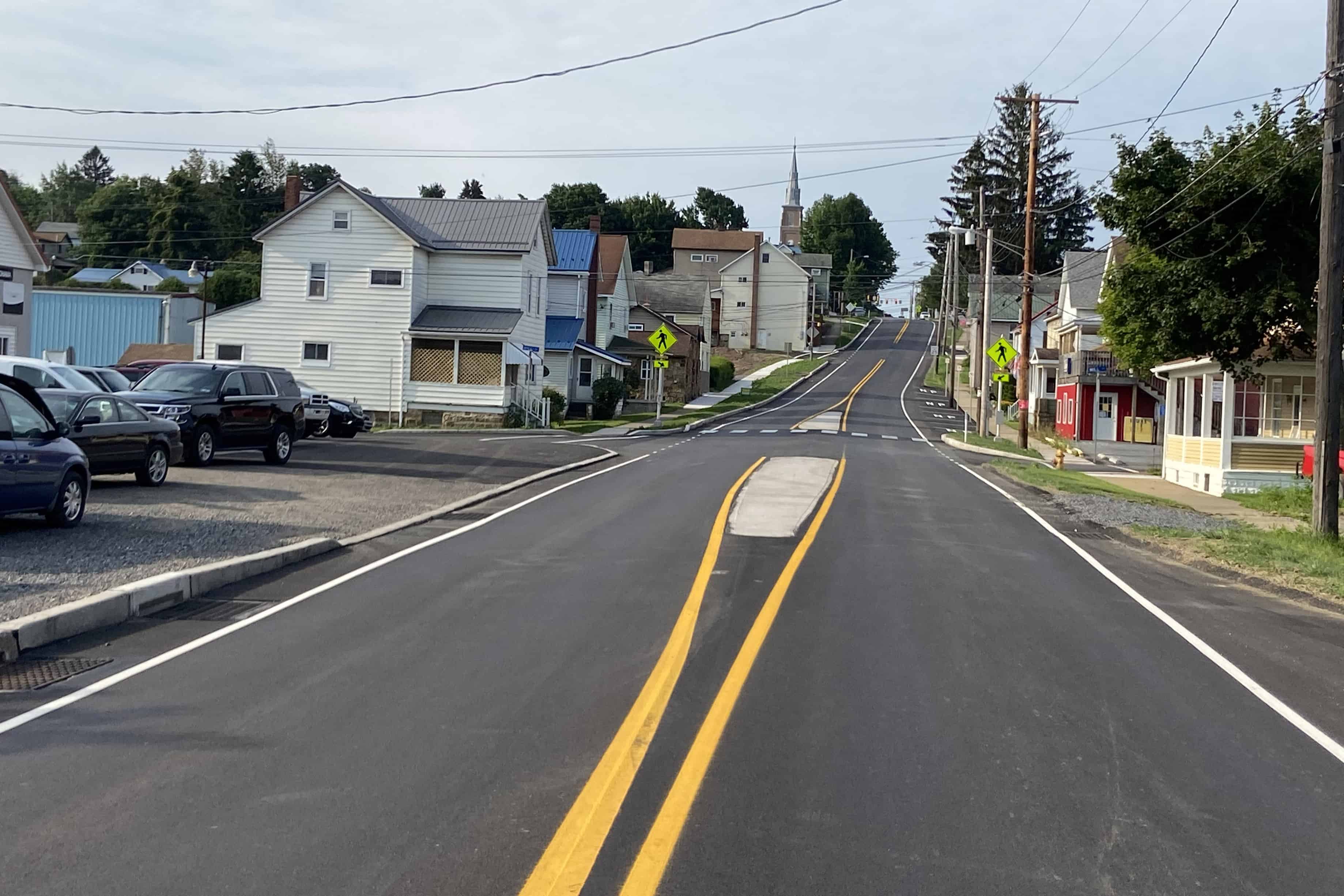 Freshly paved two-lane Route 219 runs throughs a town with buildings on either side.
